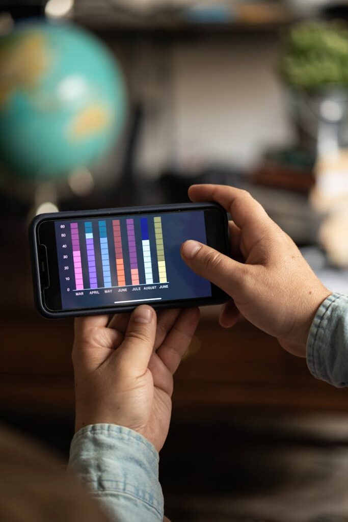 Close-up of a smartphone displaying colorful data charts held by hands, showcasing digital analytics.